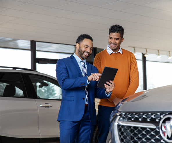 Salesman showing a customer car details on a tablet.